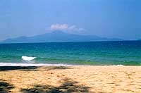 Spiaggia su Sibu Island, con un'isola vulcano all'orizzonte